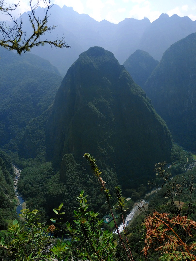 A river winding itself between very step, overgrown mountains