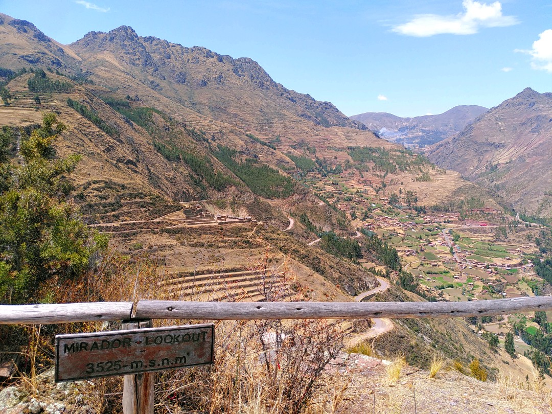 View into an Andean valley with a wooden sign designating the lookout as 3525 meters over sea level