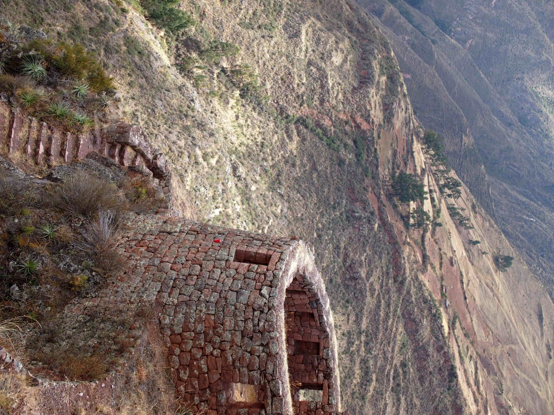 An old stone tower with green-brown Andean mountains in the background