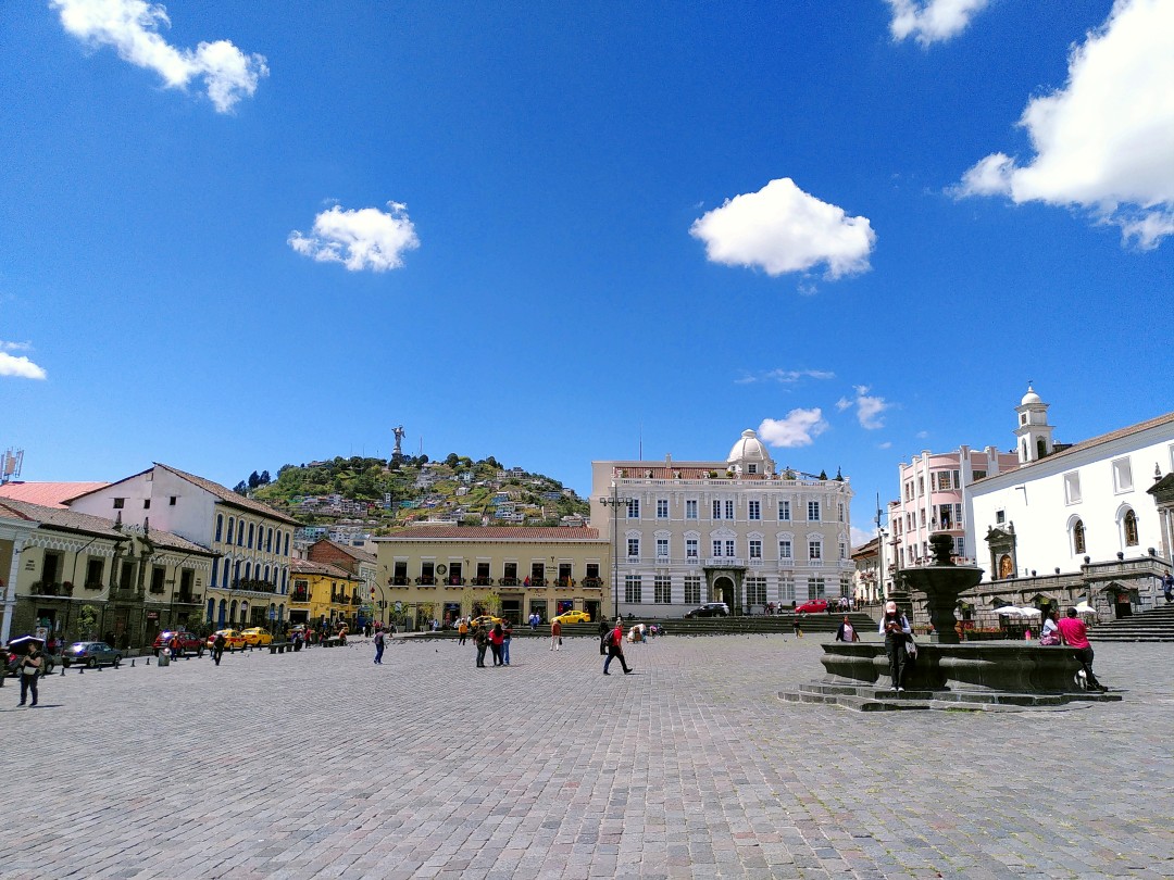 Plaza San Francisco, surrounded by colonial style buildings and a hill with a monument on it in the back