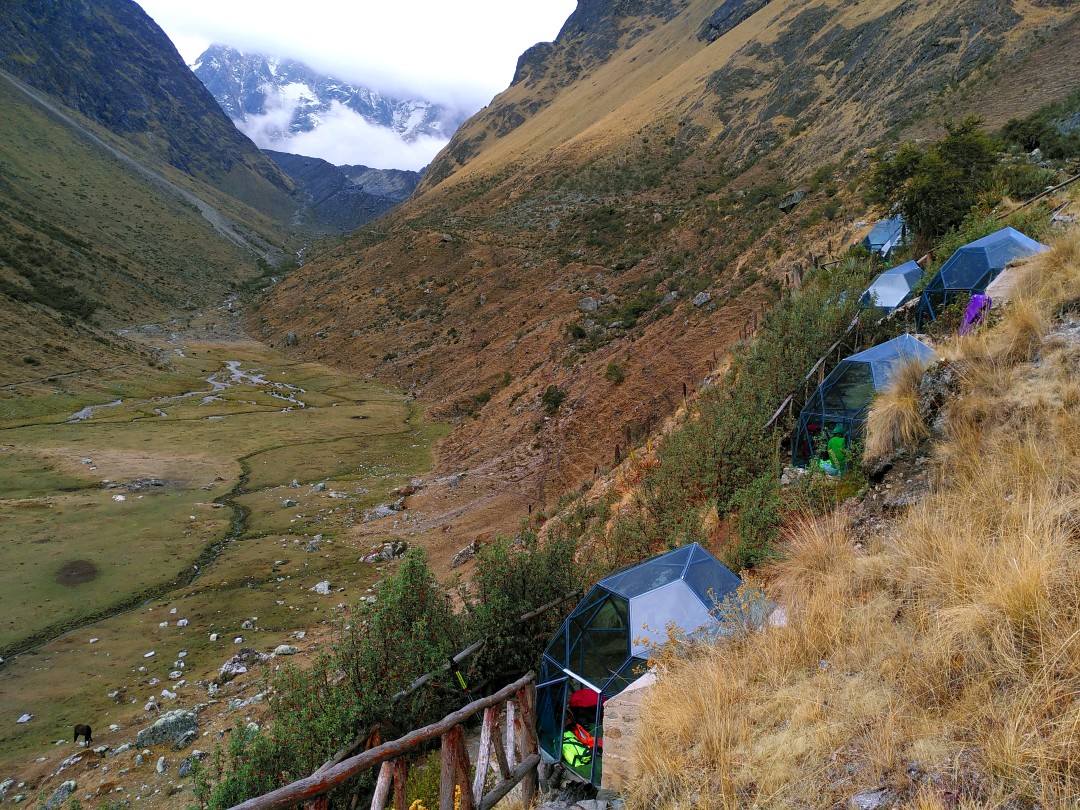 Glass igloos on the flank of a mountain with view into a long valley