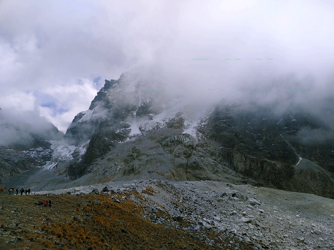 A field of rocks in front of the Salkantay mountain, which reaches into the clouds